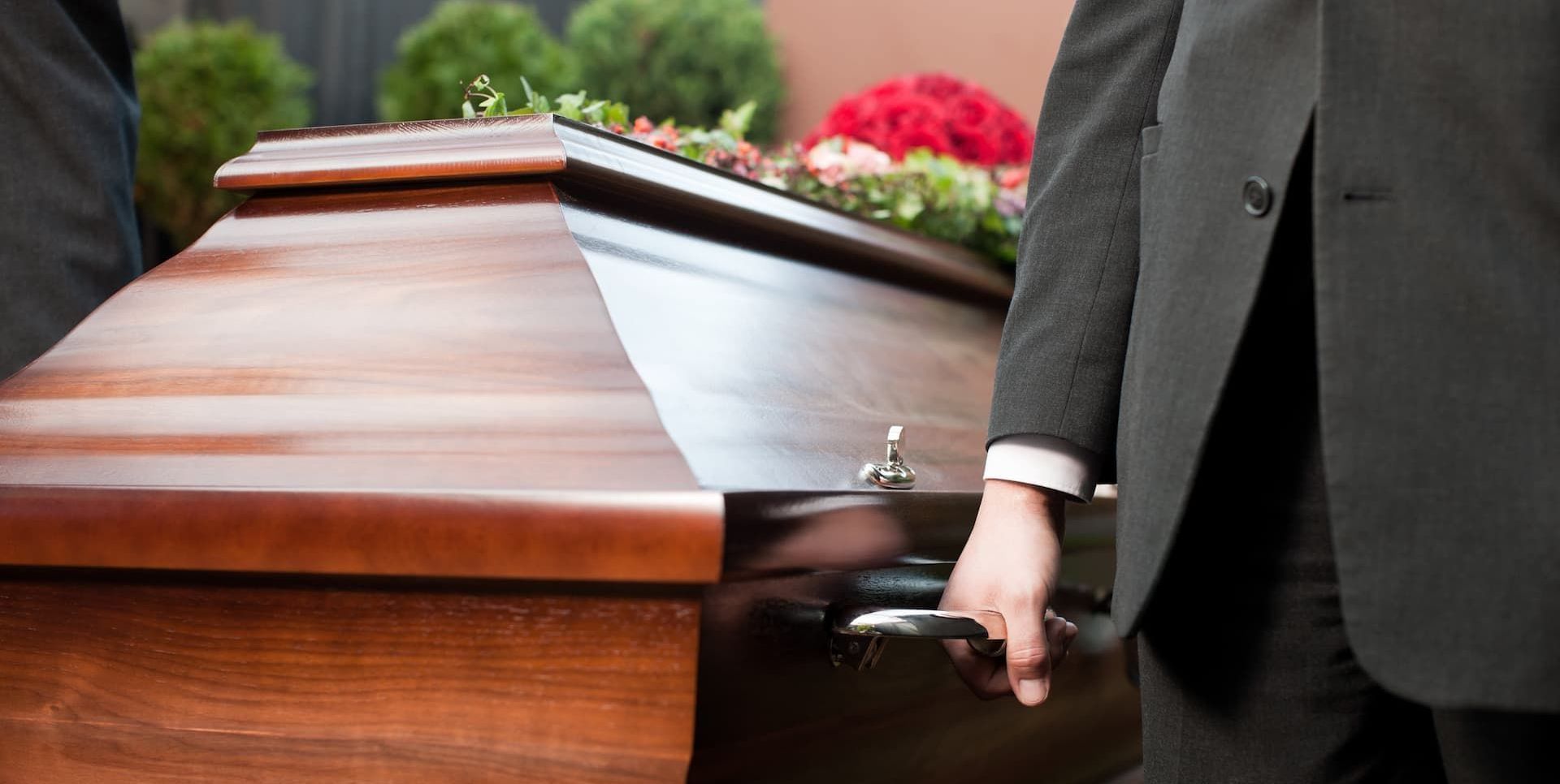 a woman is holding a red rose in front of a coffin .