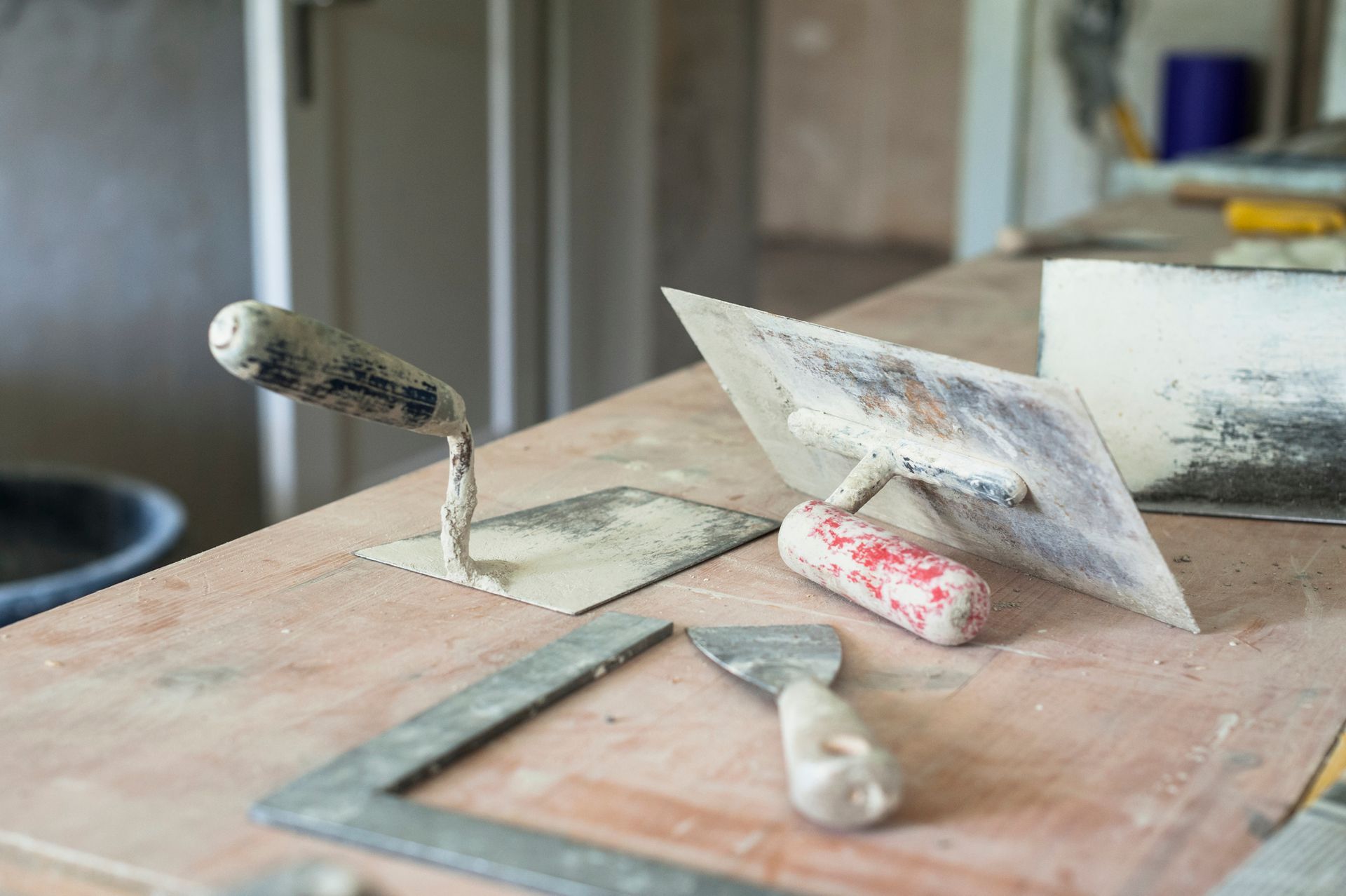 Una cazzuola, una spatola e un righello sono su un tavolo di legno.
