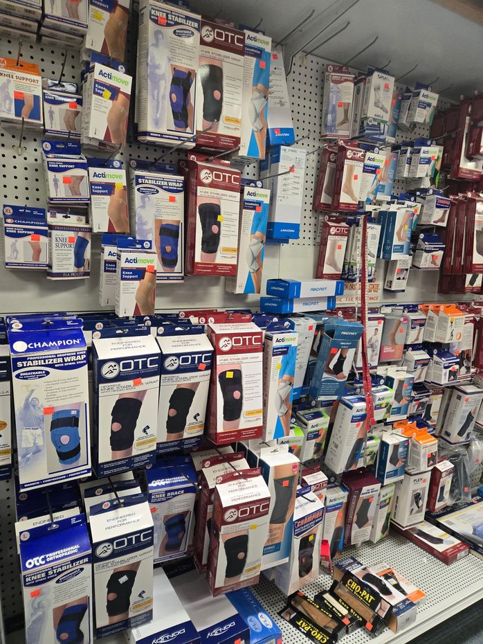 Shelves stocked with various knee braces and supports in a retail store.