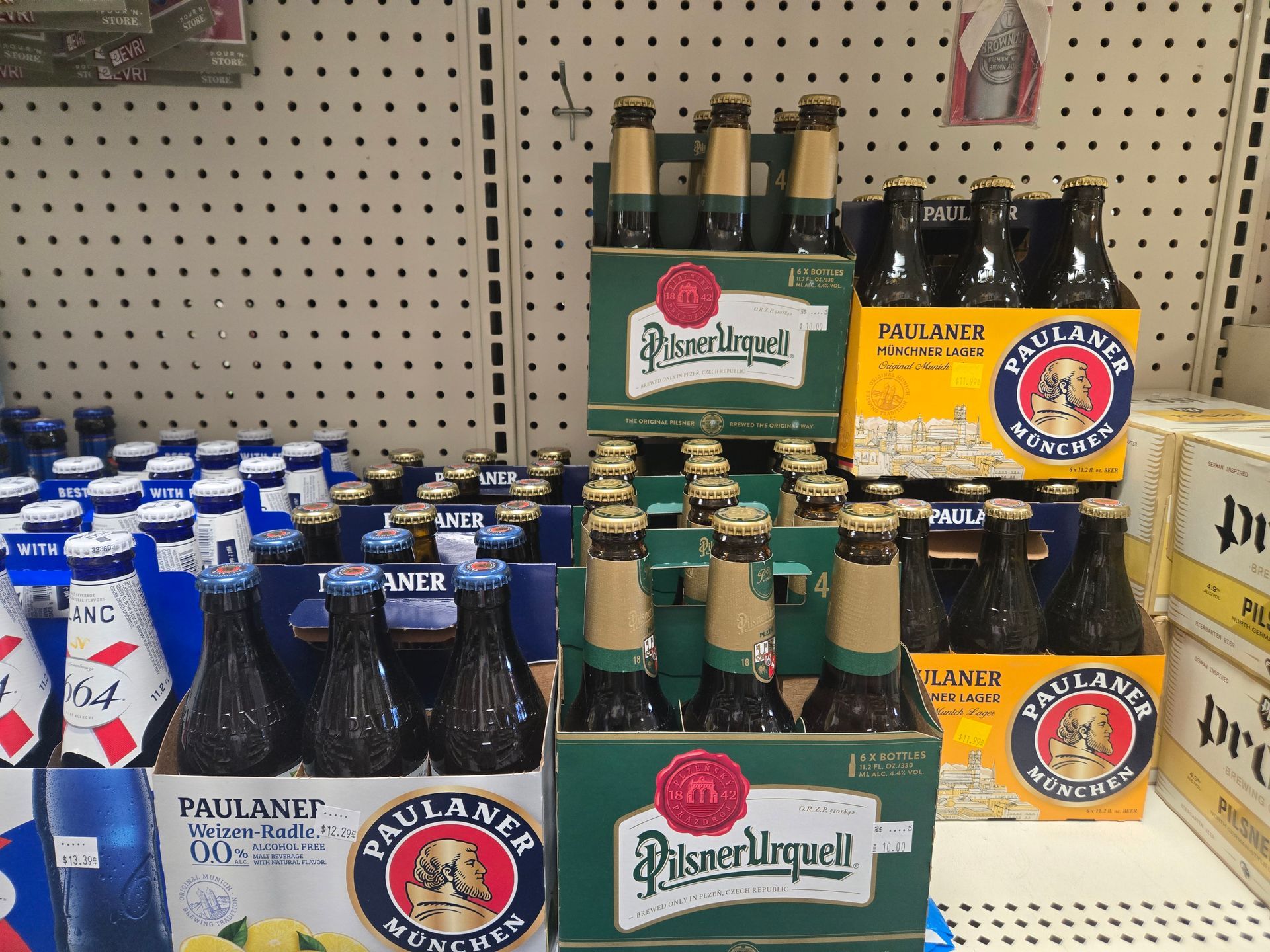 Shelves of beer bottles and cases in a store. Bottles of Pilsner Urquell and Paulaner Munich beers.