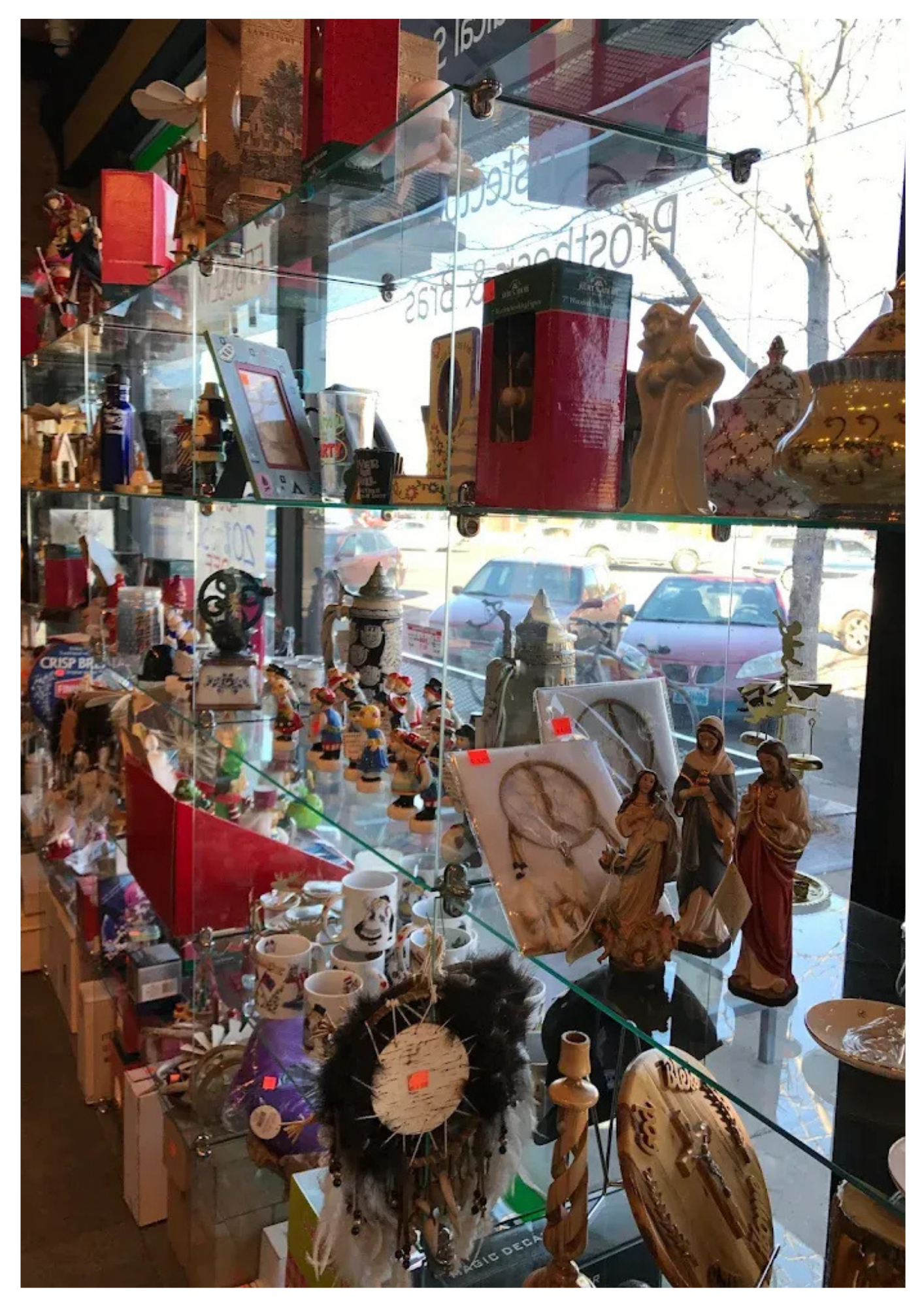 Glass display case filled with various items for sale, like figurines and decor. Light from window reflects on the glass.