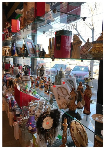 Glass display case filled with various items for sale, like figurines and decor. Light from window reflects on the glass.