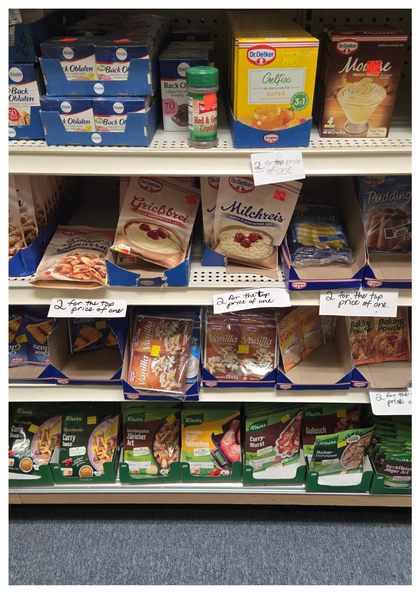 Shelves in a store stocked with boxes of food products, including cake mixes and spices.