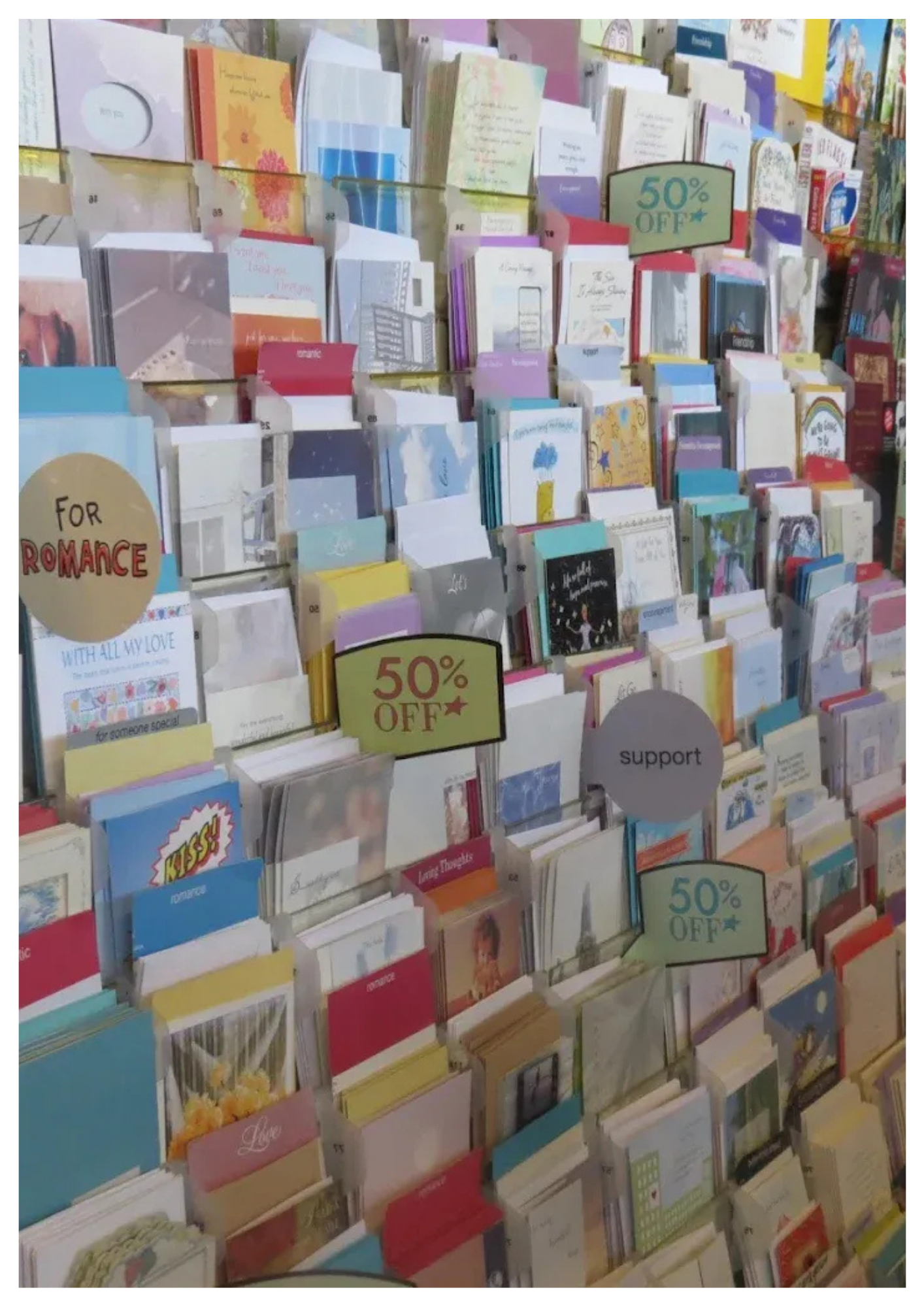 Greeting cards displayed on a store rack with signs indicating 50% off.