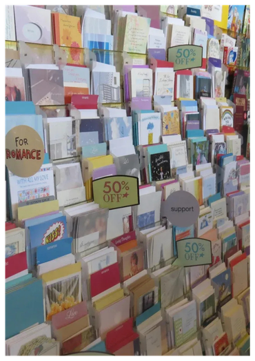 Greeting cards displayed on a store rack with signs indicating 50% off.