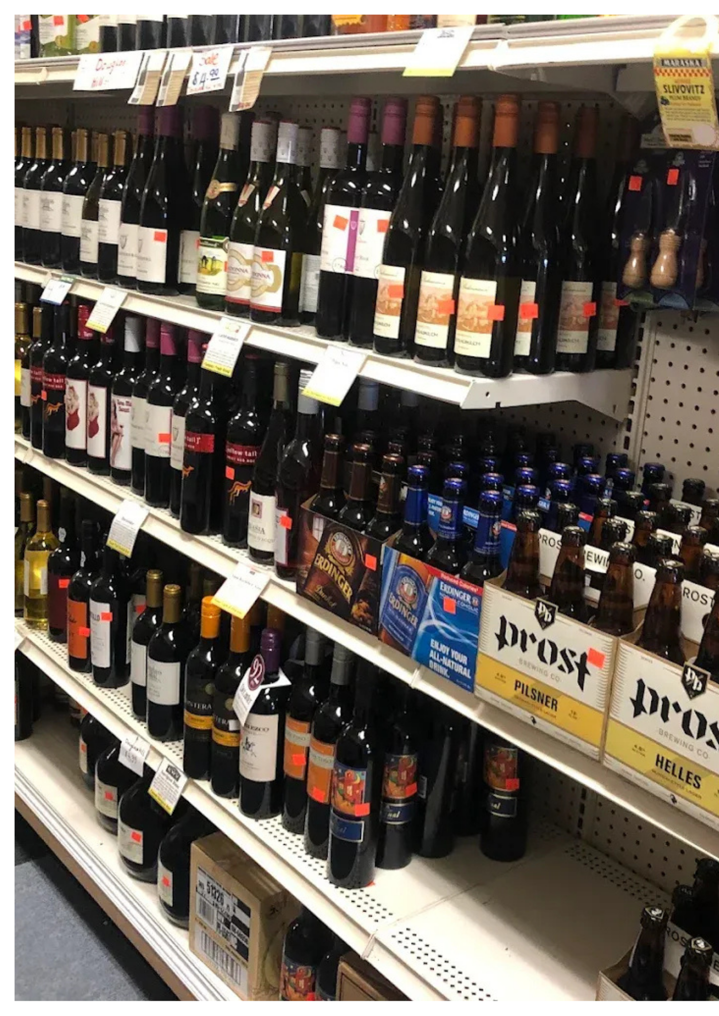 Shelves stocked with various wine and beer bottles in a store.