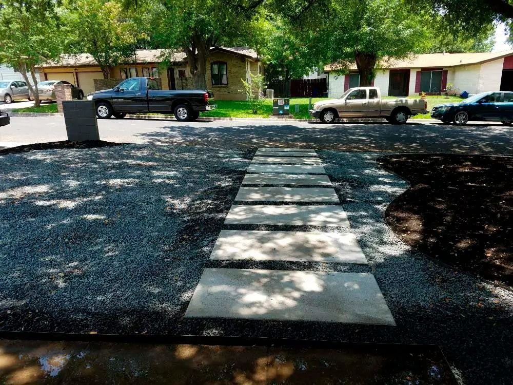 Front walkway leading to a house, with cars parked along a tree-lined residential street.