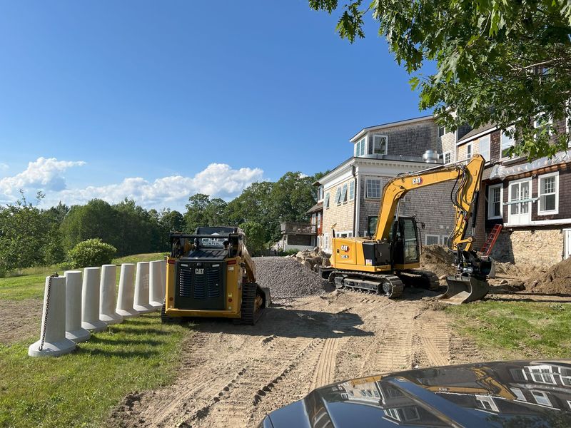 Construction site with heavy machinery: excavator, roller, bulldozer, at sunset.