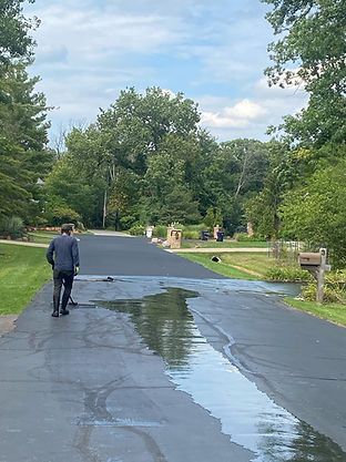 A man is walking down a wet road next to a mailbox.