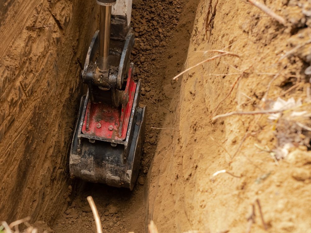 Small Excavator Digging a Narrow Trench in Brown Soil — Bigfoot Earthmoving In Byron Bay, NSW