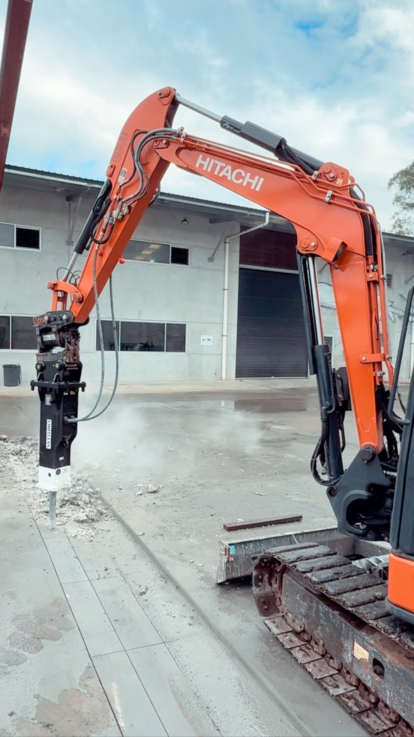 Orange Hitachi Excavator with A Jackhammer Attachment Breaking Concrete — Bigfoot Earthmoving In Byron Bay, NSW