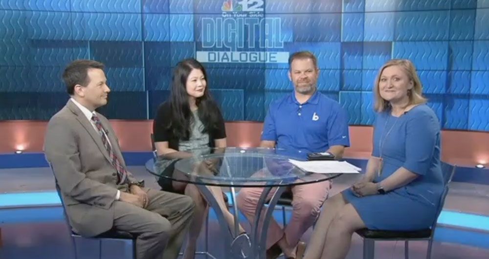 A group of people are sitting around a table on a television set.