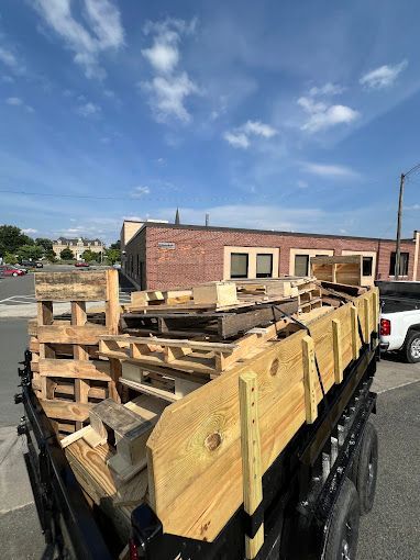 A trailer filled with wooden pallets is parked on the side of the road.