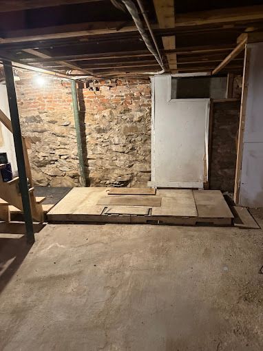A basement with a brick wall and a wooden floor.