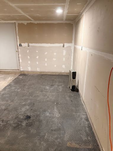 A room with a gray floor and white walls is being remodeled.