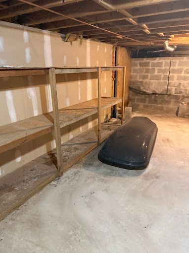 A basement with shelves and a roof box on the floor.