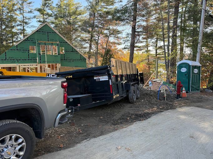 A truck and trailer are parked in front of a house under construction.