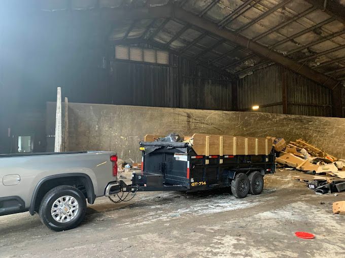 A truck is towing a dumpster in a warehouse.