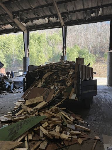 A pile of wood is sitting under a roof in a building.