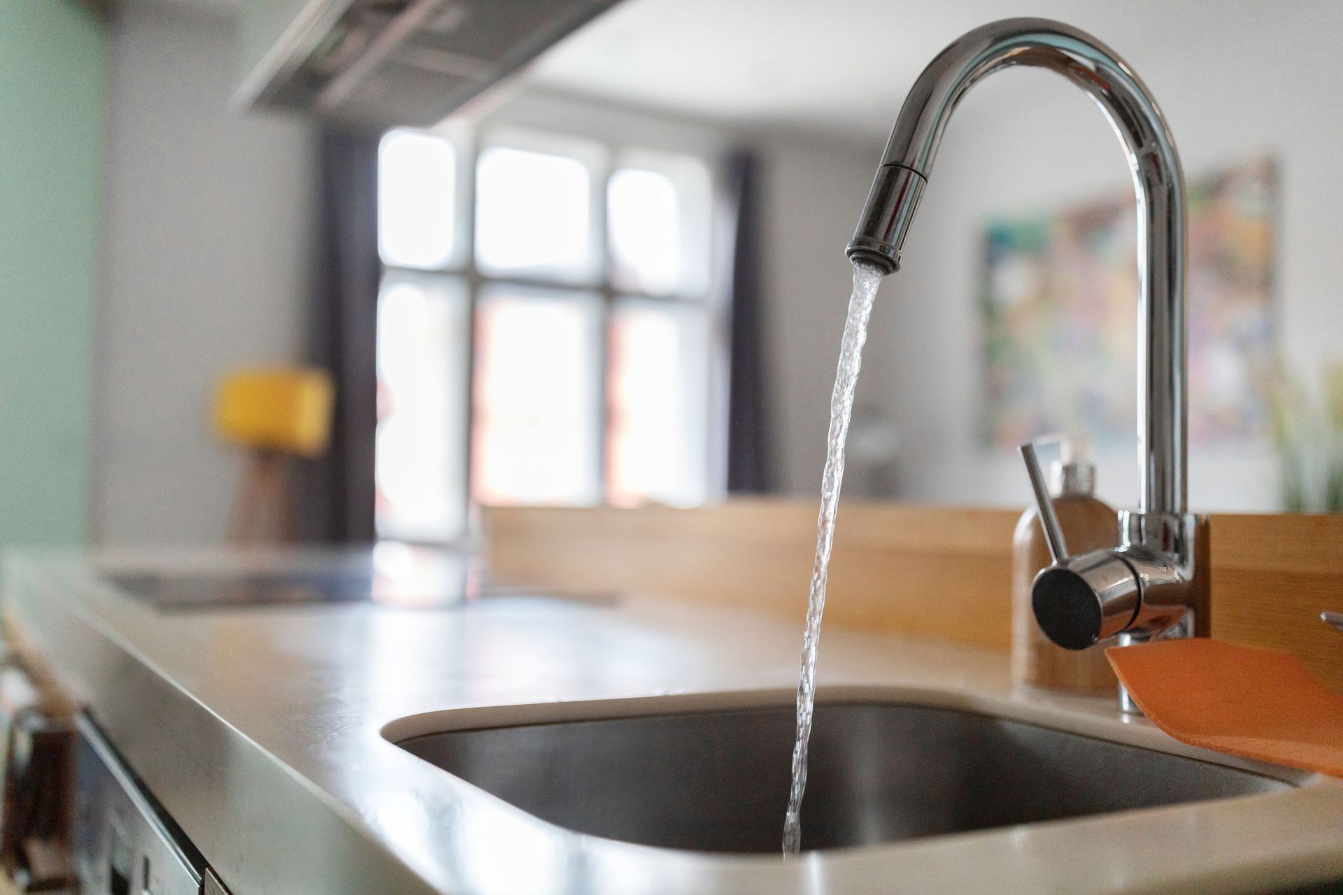 A kitchen sink with water running from the faucet.