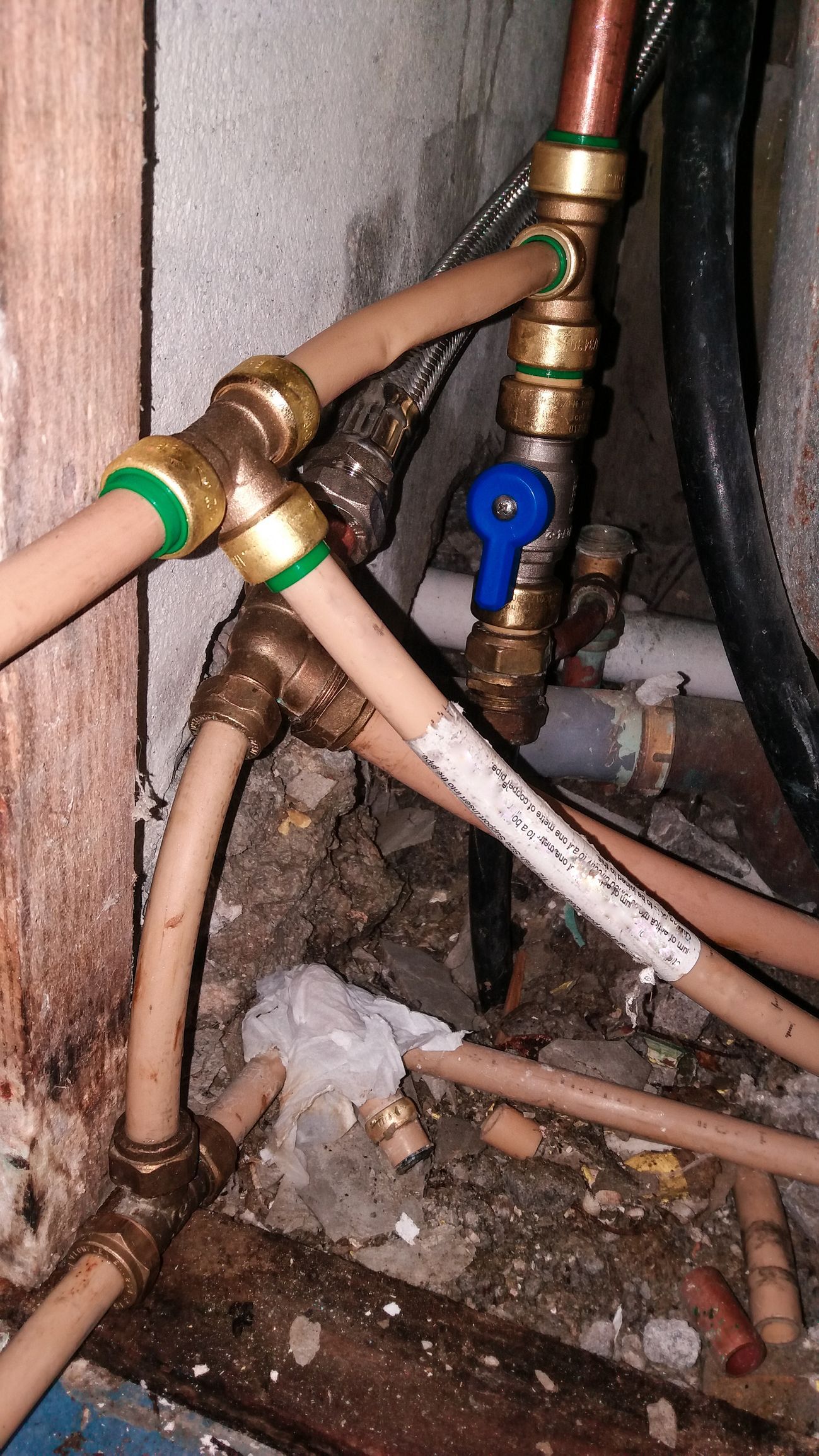 A white water heater is hanging on a blue tiled wall in a bathroom.