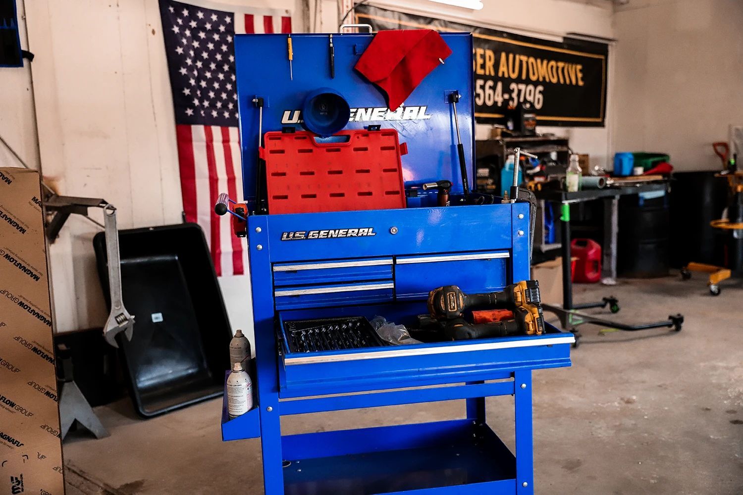 Blue tool cart with drawers and tools in an auto shop, with an American flag in the background | Kaiser Automotive