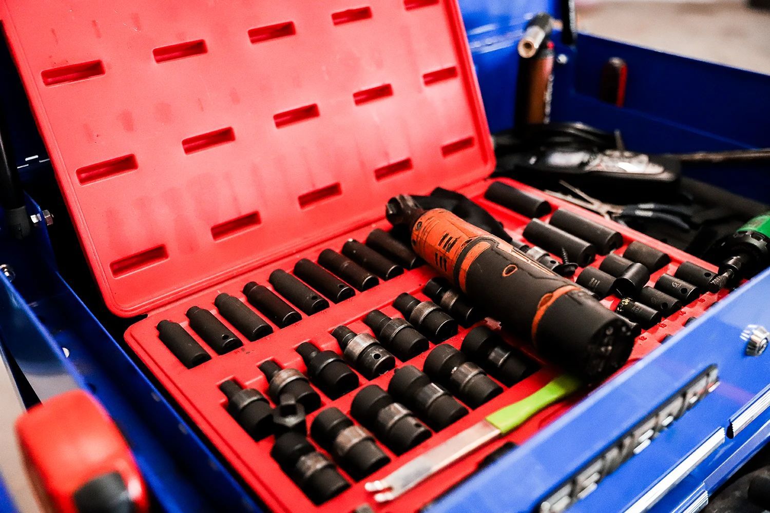 Open toolbox with red insert holding a set of black sockets and an orange impact wrench | Kaiser Automotive