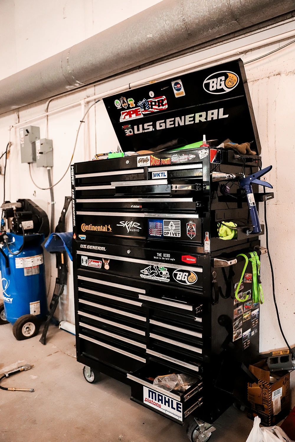 Black US General rolling tool chest in a garage, covered with stickers | Kaiser Automotive