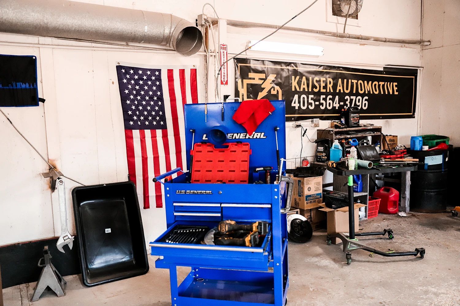 Blue tool cart in a cluttered auto shop with an American flag and Kaiser Automotive sign | Kaiser Automotive