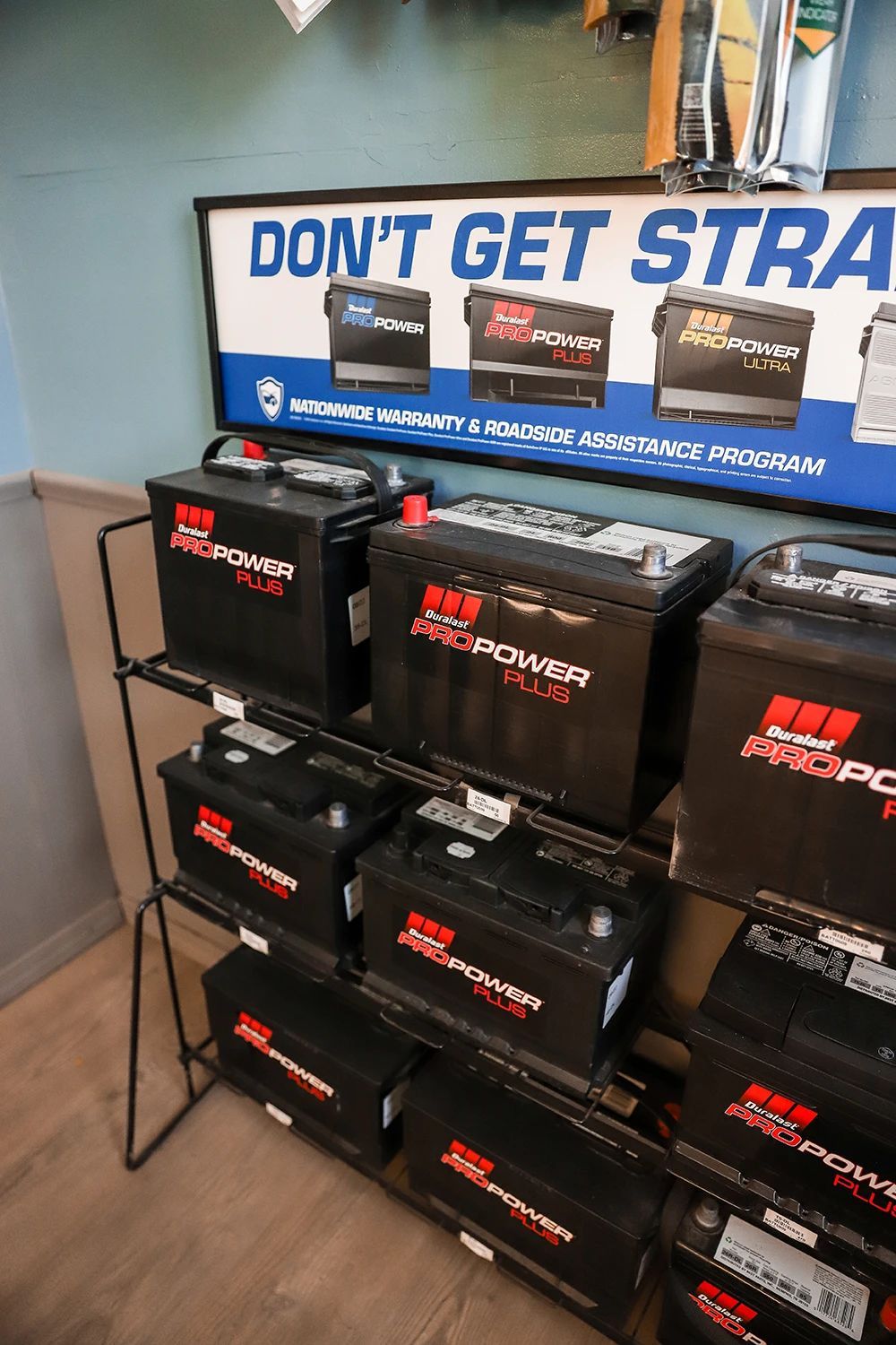 Batteries on display in a store. Black batteries with red lettering are on a black metal shelf. A sign says 