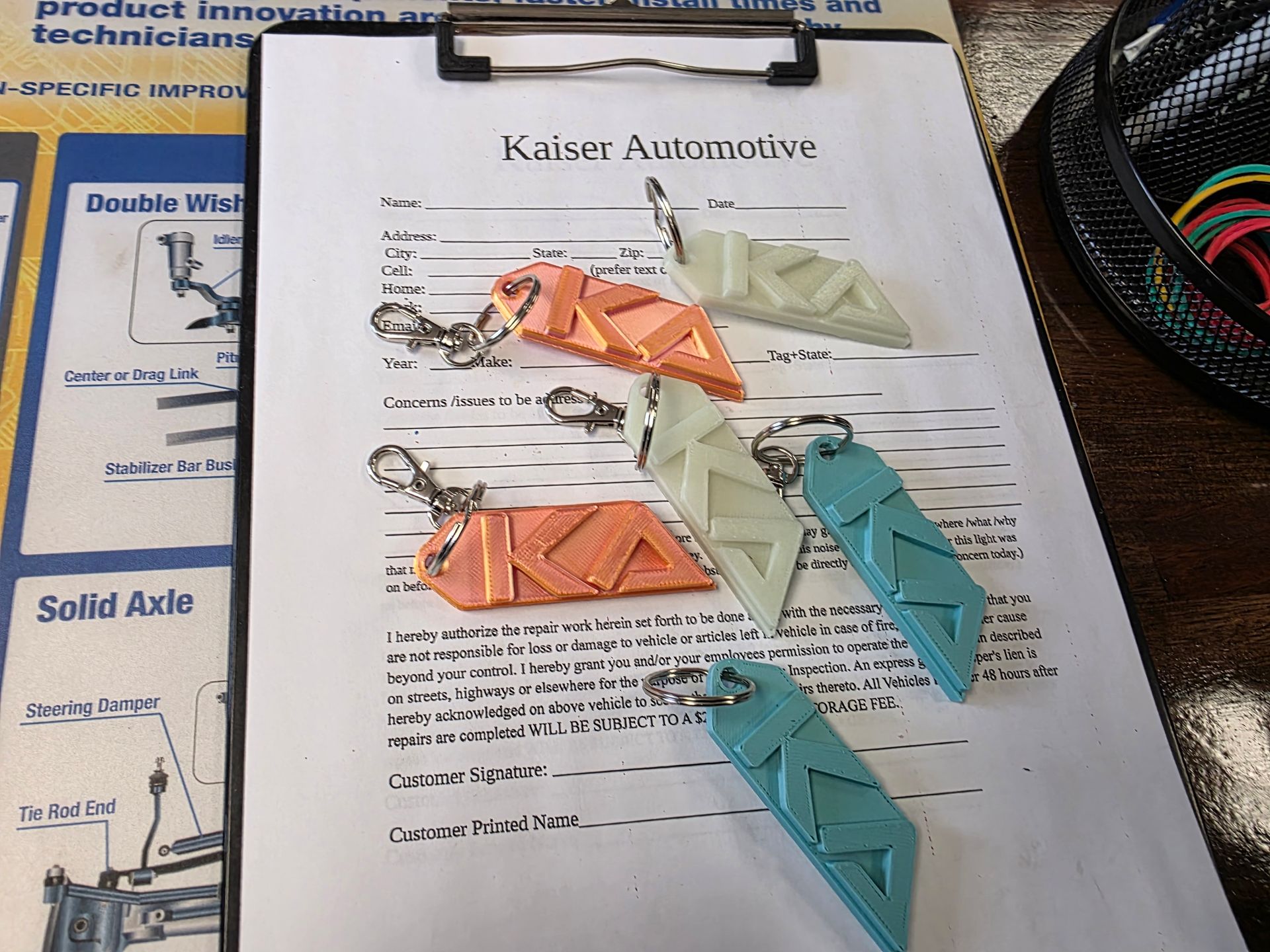 Four colored keychains with Kaiser Automotive logo on a clipboard | Kaiser Automotive Tire & Alignment