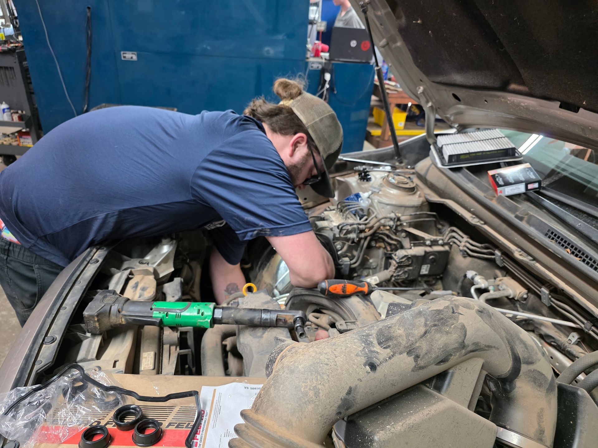 Mechanic working on car engine in a garage; using tools | Kaiser Automotive Tire & Alignment