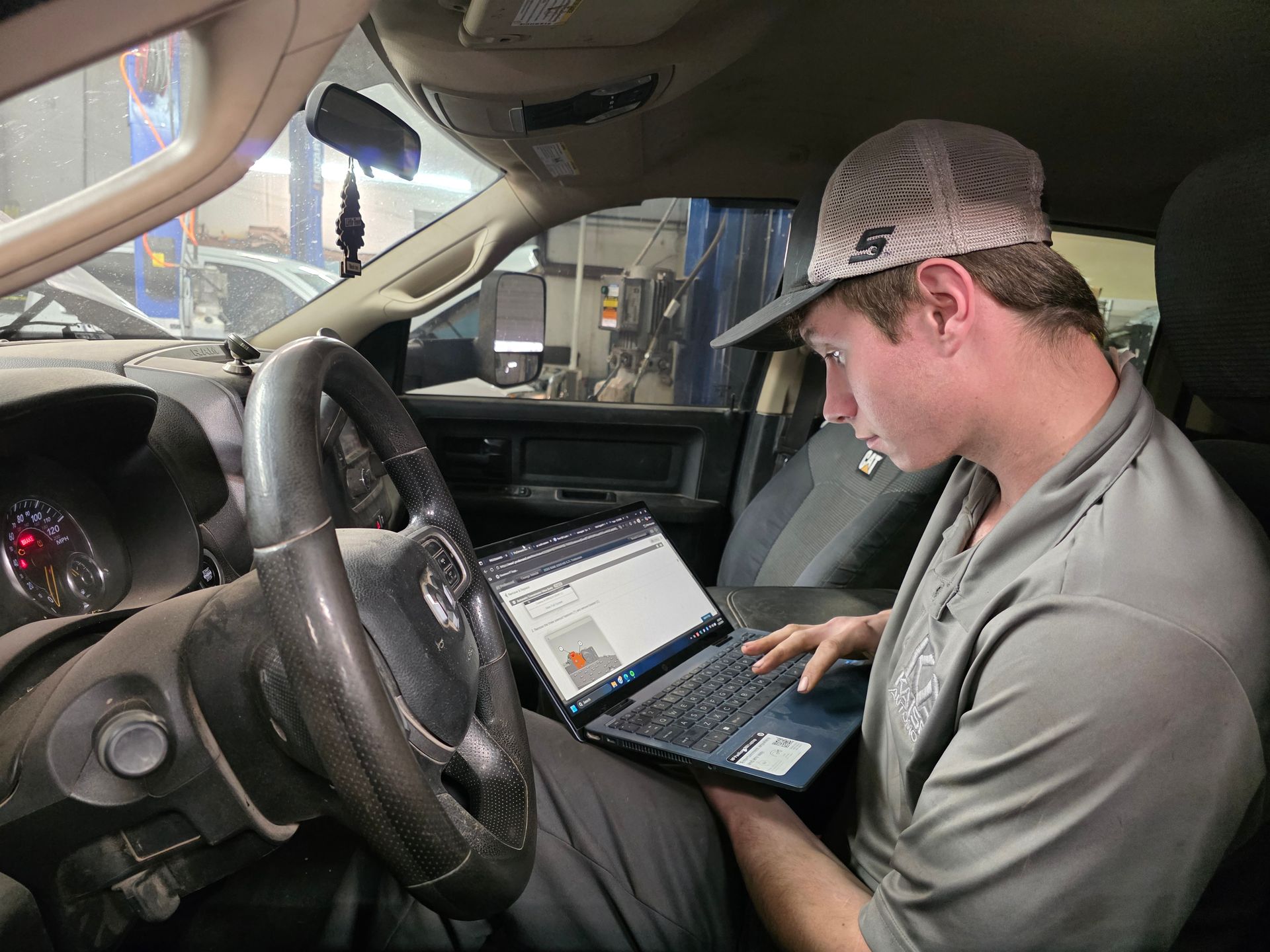 Mechanic in a truck uses a laptop to diagnose a vehicle's computer system, inside a repair shop | Kaiser Automotive Tire & Alignment