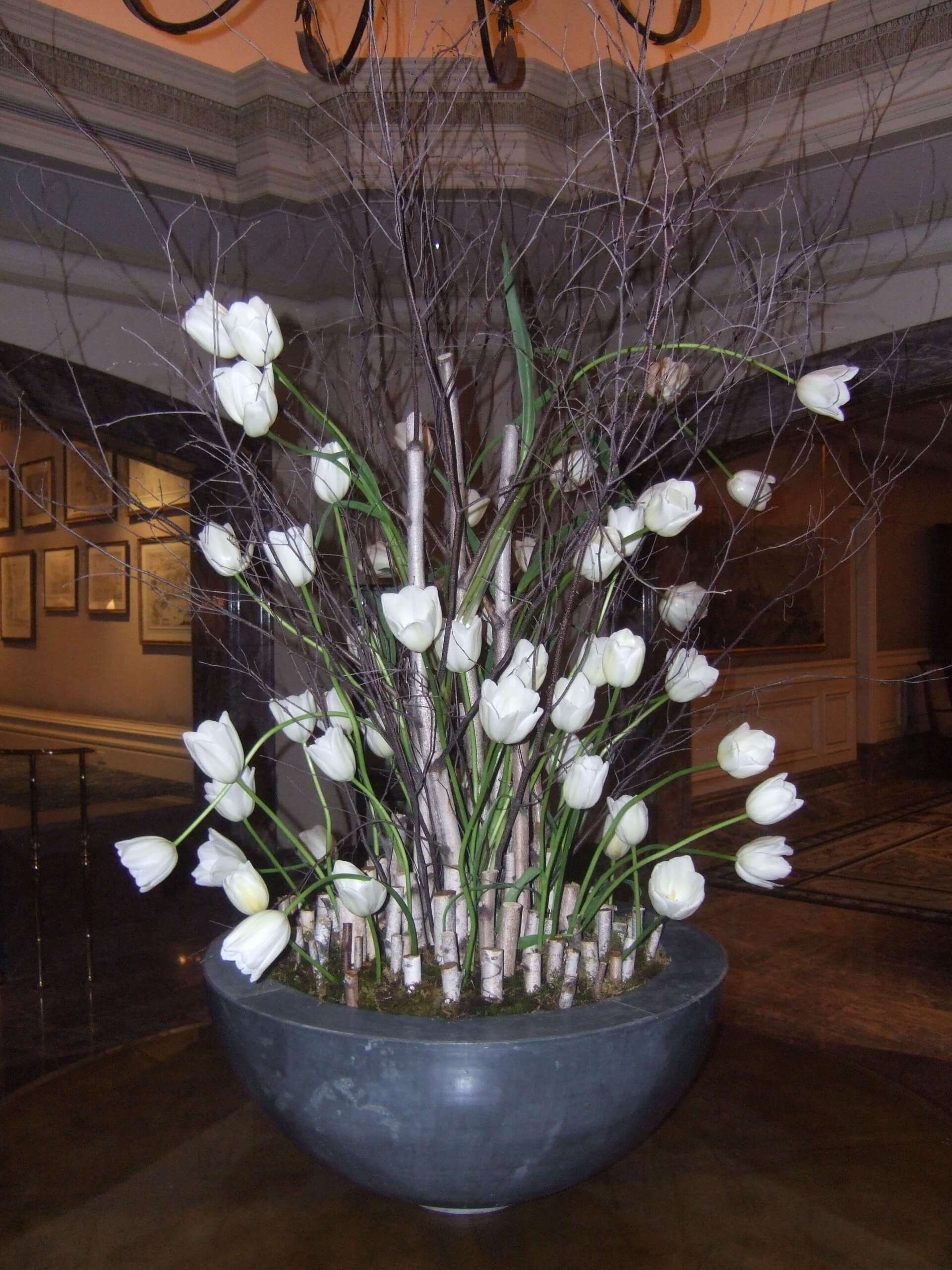 A large vase filled with white flowers and branches - flowers designed by Flowers by Leo