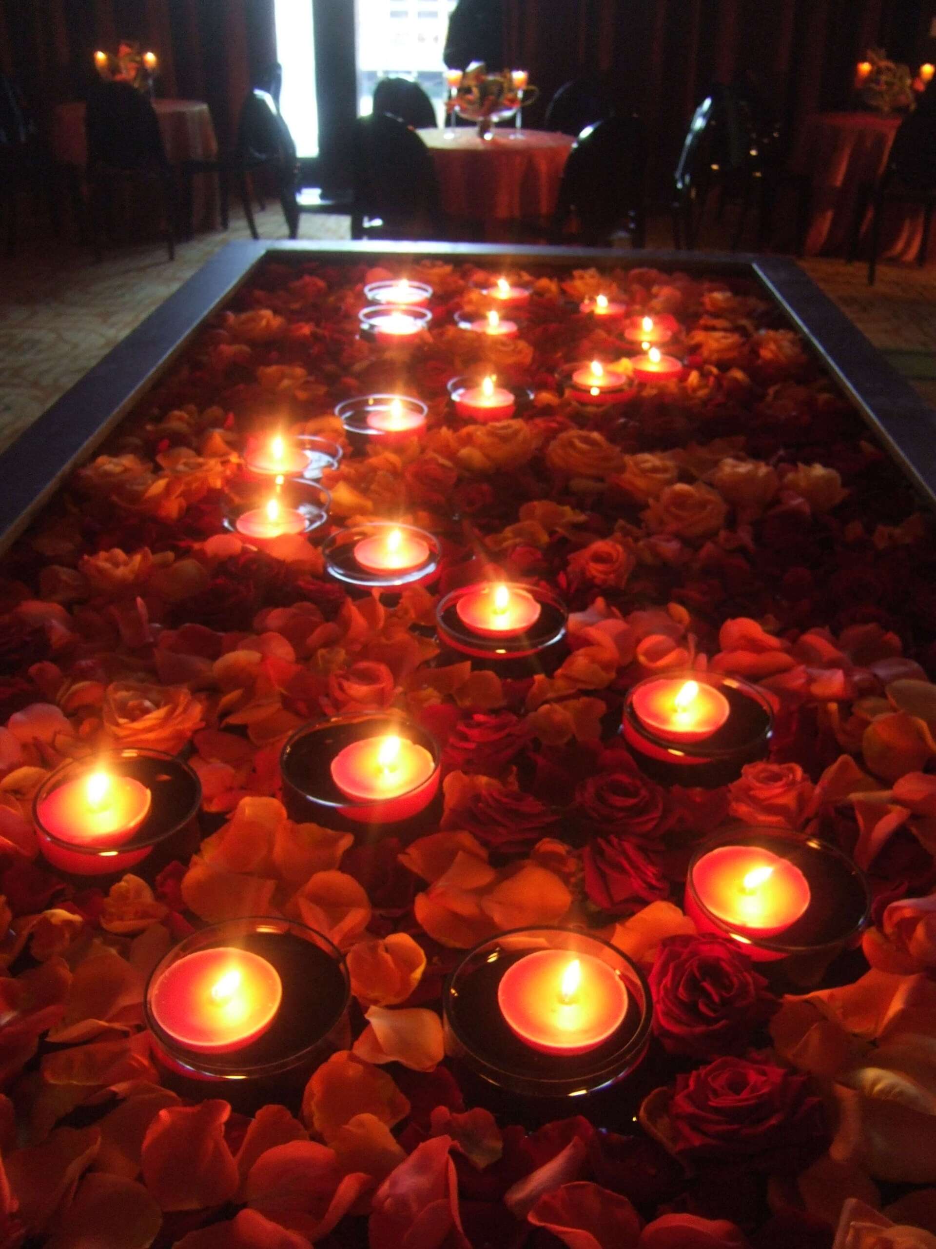 Candles are floating in a pool of rose petals - flowers designed by Flowers by Leo
