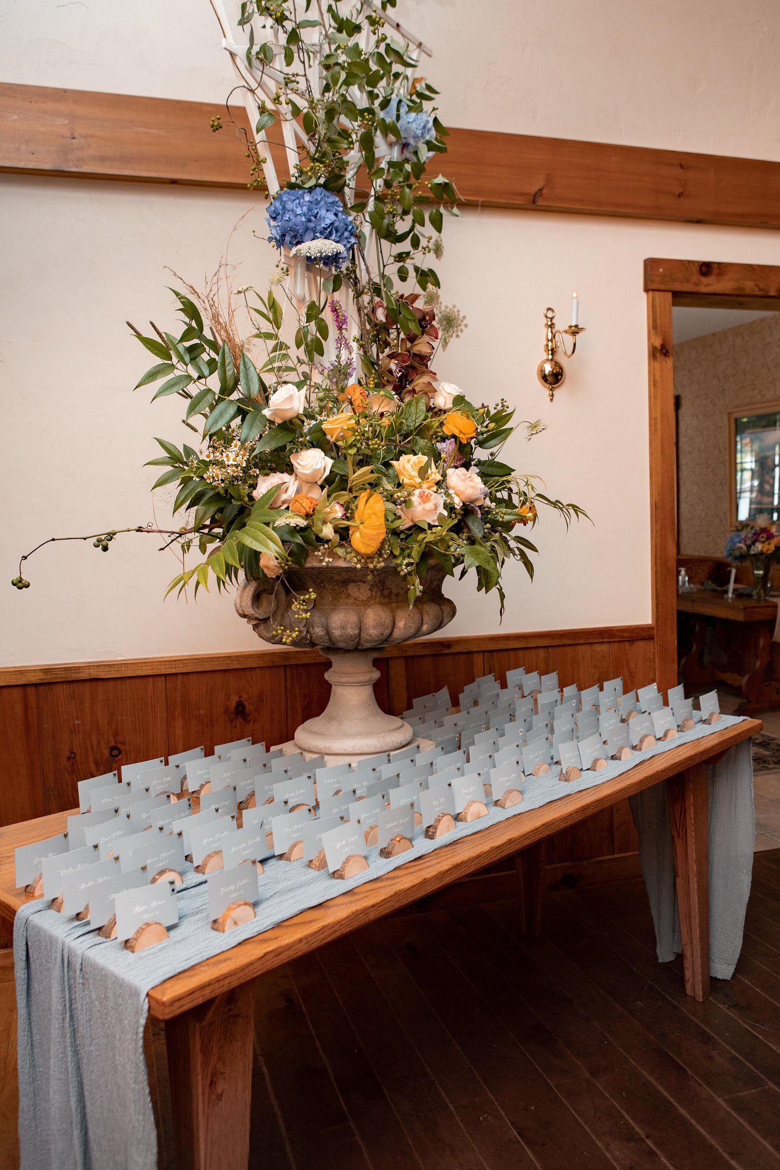 A table with a vase of flowers and place cards on it - flowers designed by Flowers by Leo.