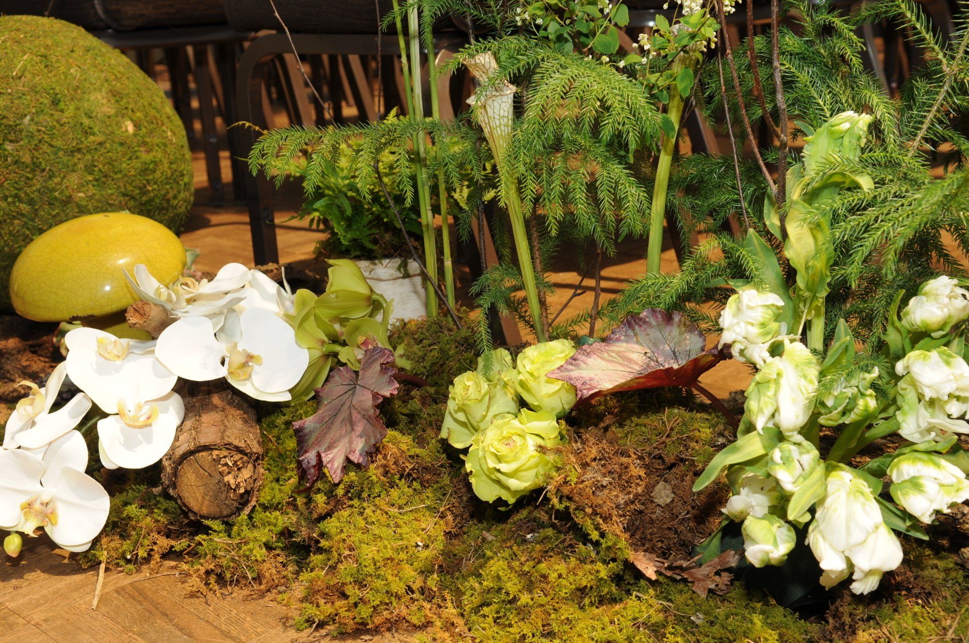 A bunch of flowers are sitting on top of a mossy surface - flowers designed by Flowers by Leo.