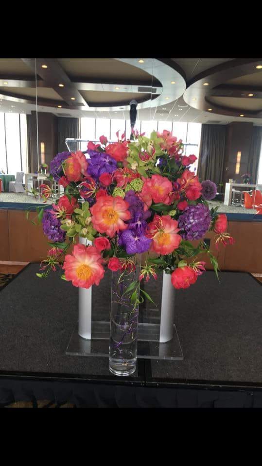 A vase filled with colorful flowers is on a table - flowers designed by Flowers by Leo.