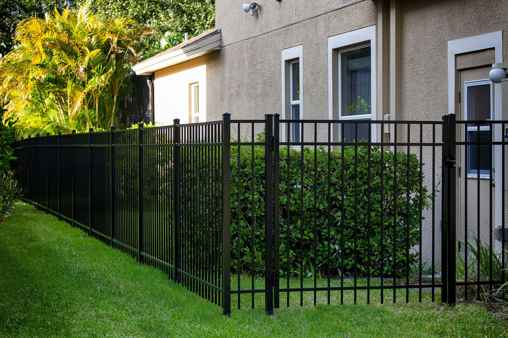 a black fence surrounds a lush green yard in front of a house .