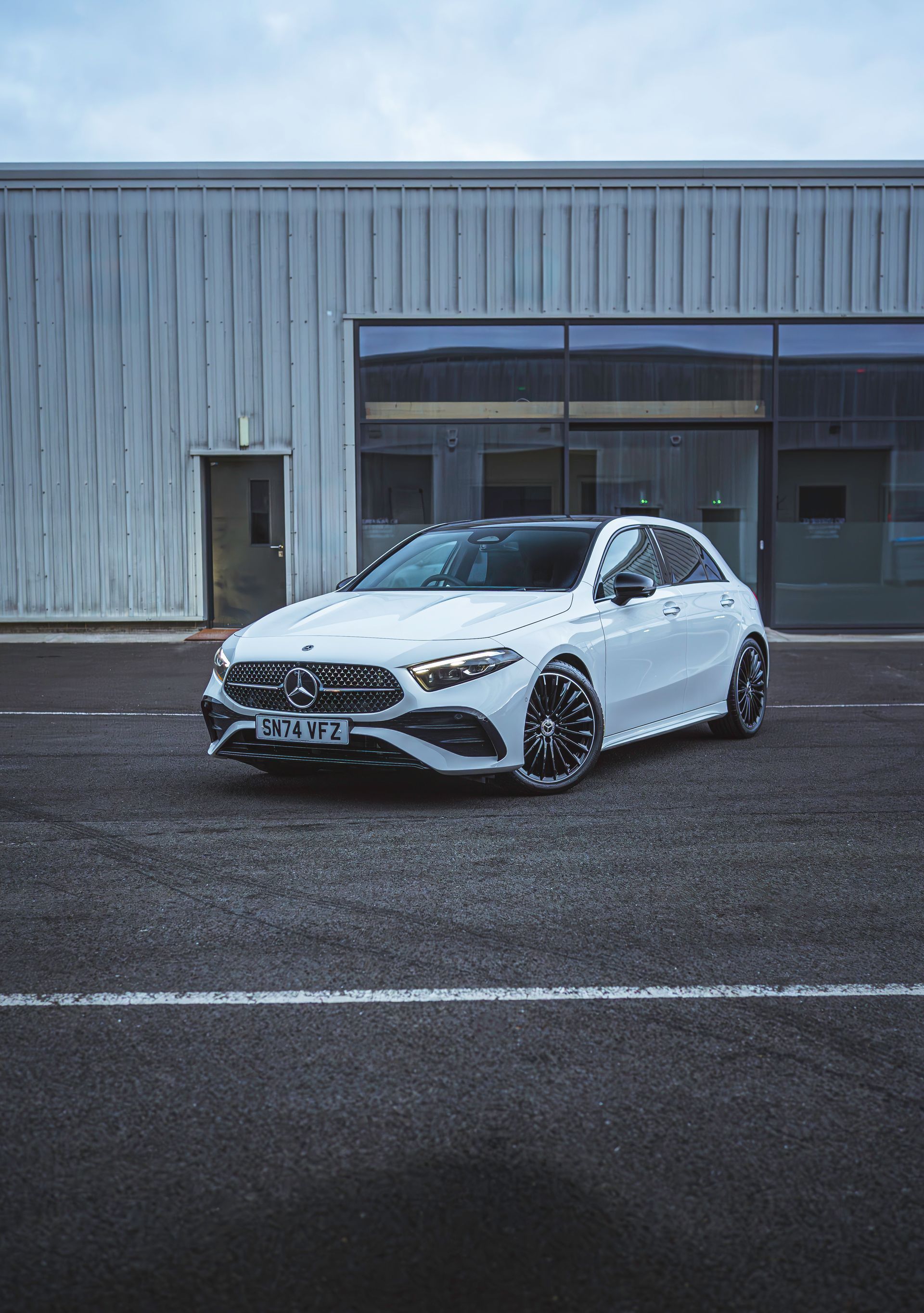 A white car is parked in front of a building.