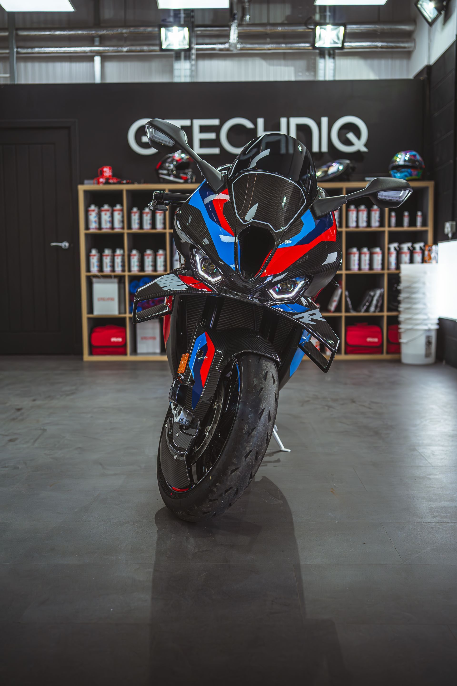 A red , white and blue motorcycle is parked in a garage.
