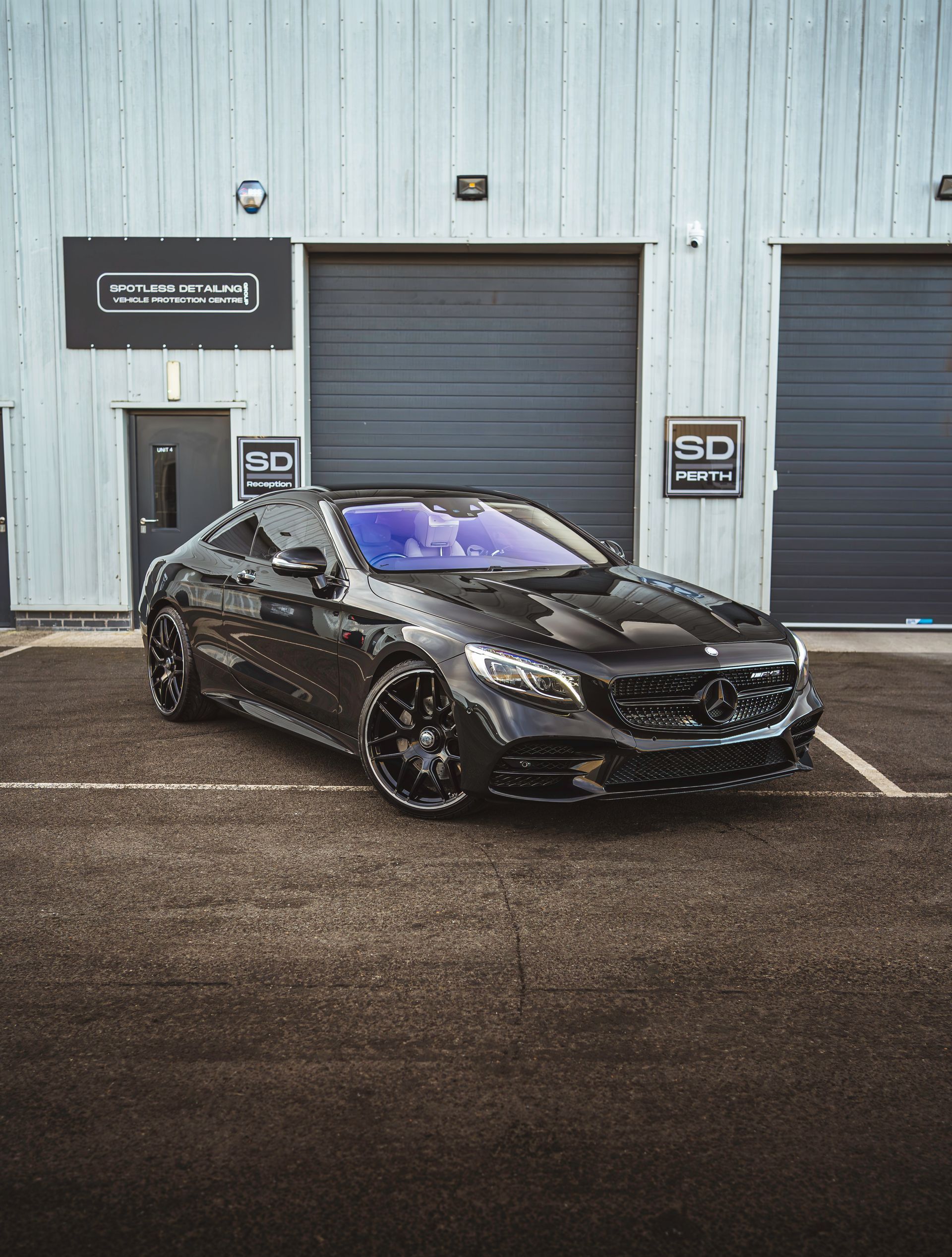 A black car is parked in front of a building.