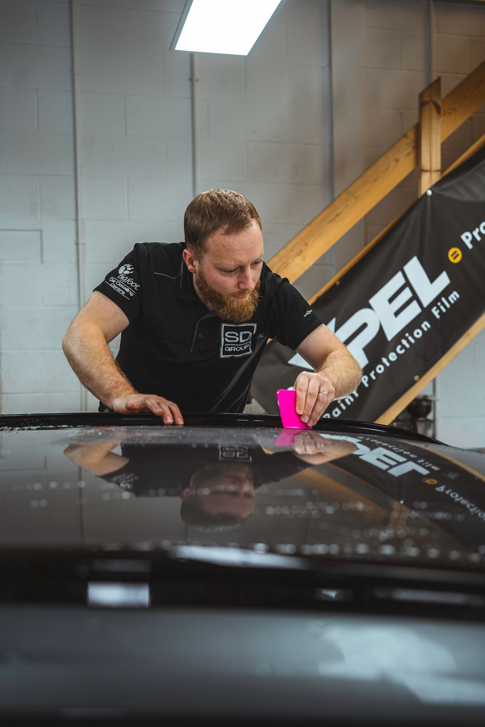 A man is applying a film to the roof of a car.