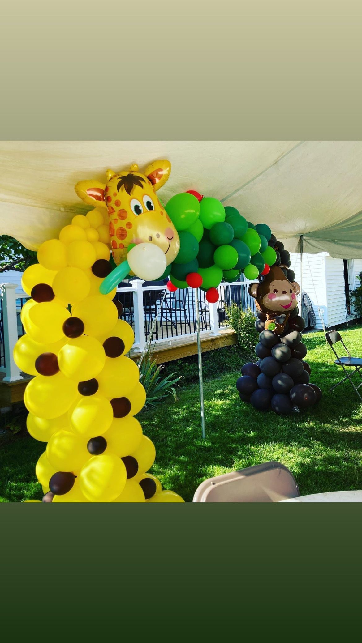 A giraffe and monkey made out of balloons are sitting under a tent.