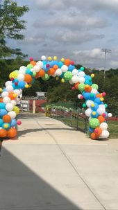 A colorful balloon arch is sitting on the side of a road.