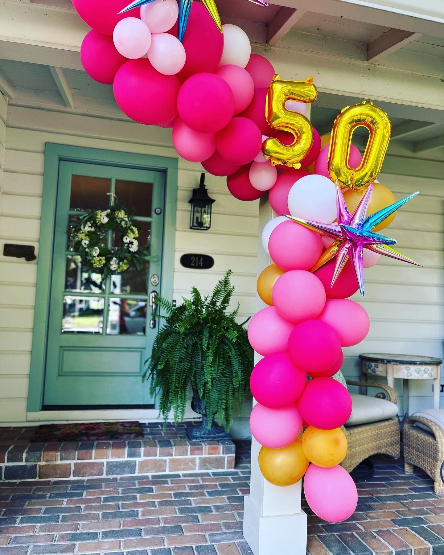 A porch decorated with pink and gold balloons for a 50th birthday