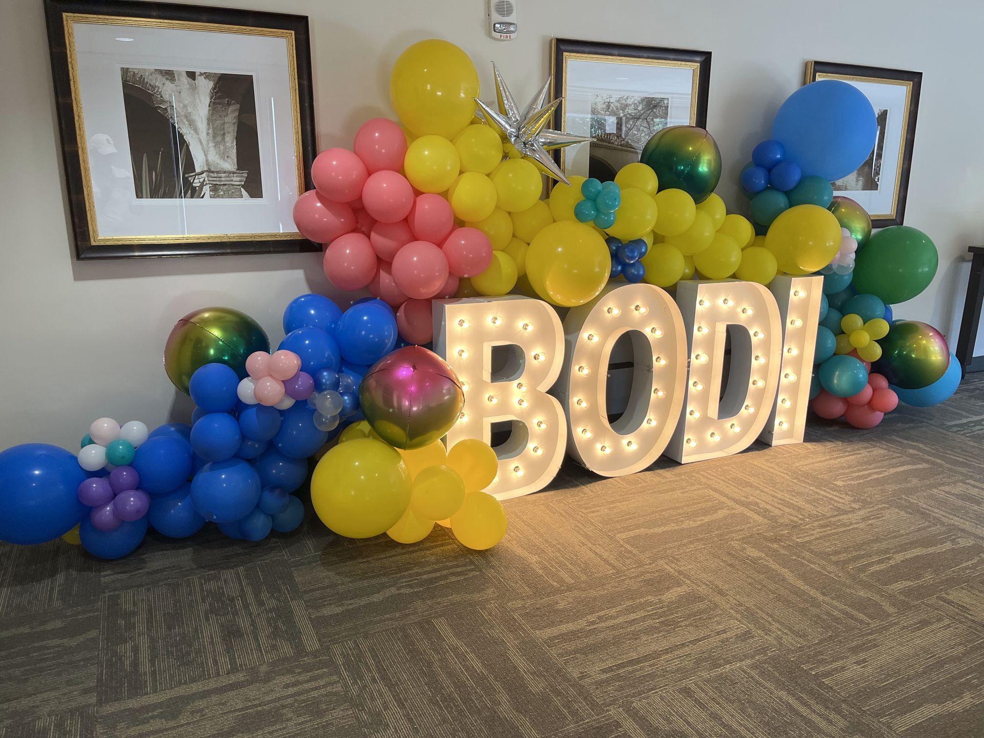 Blue and yellow balloons in front of a sign that says olympus