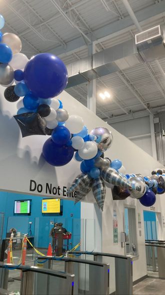 A bunch of blue and white balloons are hanging from the ceiling of a building.