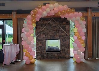A room with a fireplace and a balloon arch in front of it.