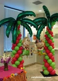 A room decorated with palm trees and monkeys made of balloons.